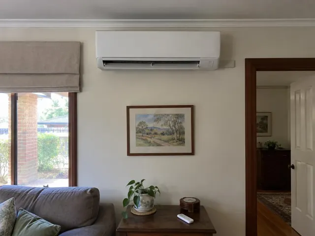Wall-mounted split system running above a living room wall, with louvre open, in Cumberland Park