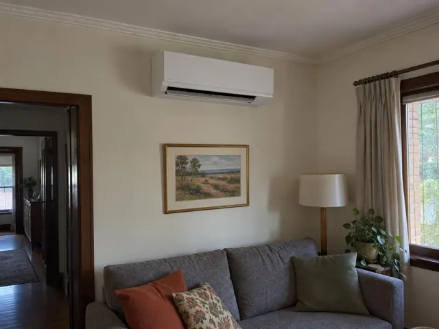 Living room with a wall-mounted split system above a sofa and framed artwork in Edwardstown