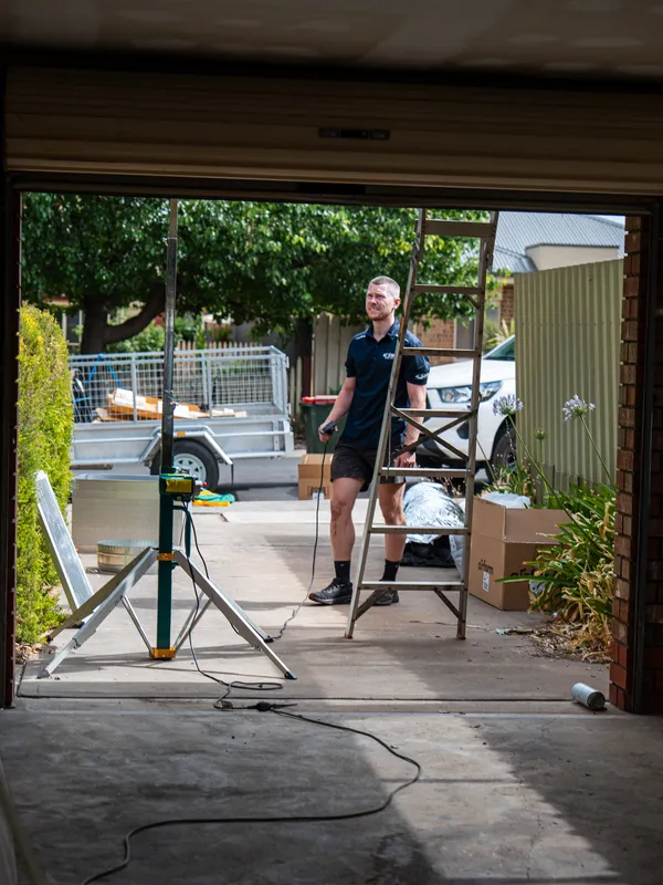 Technician on a driveway with a ladder and flexible ducting ready for a ducted install